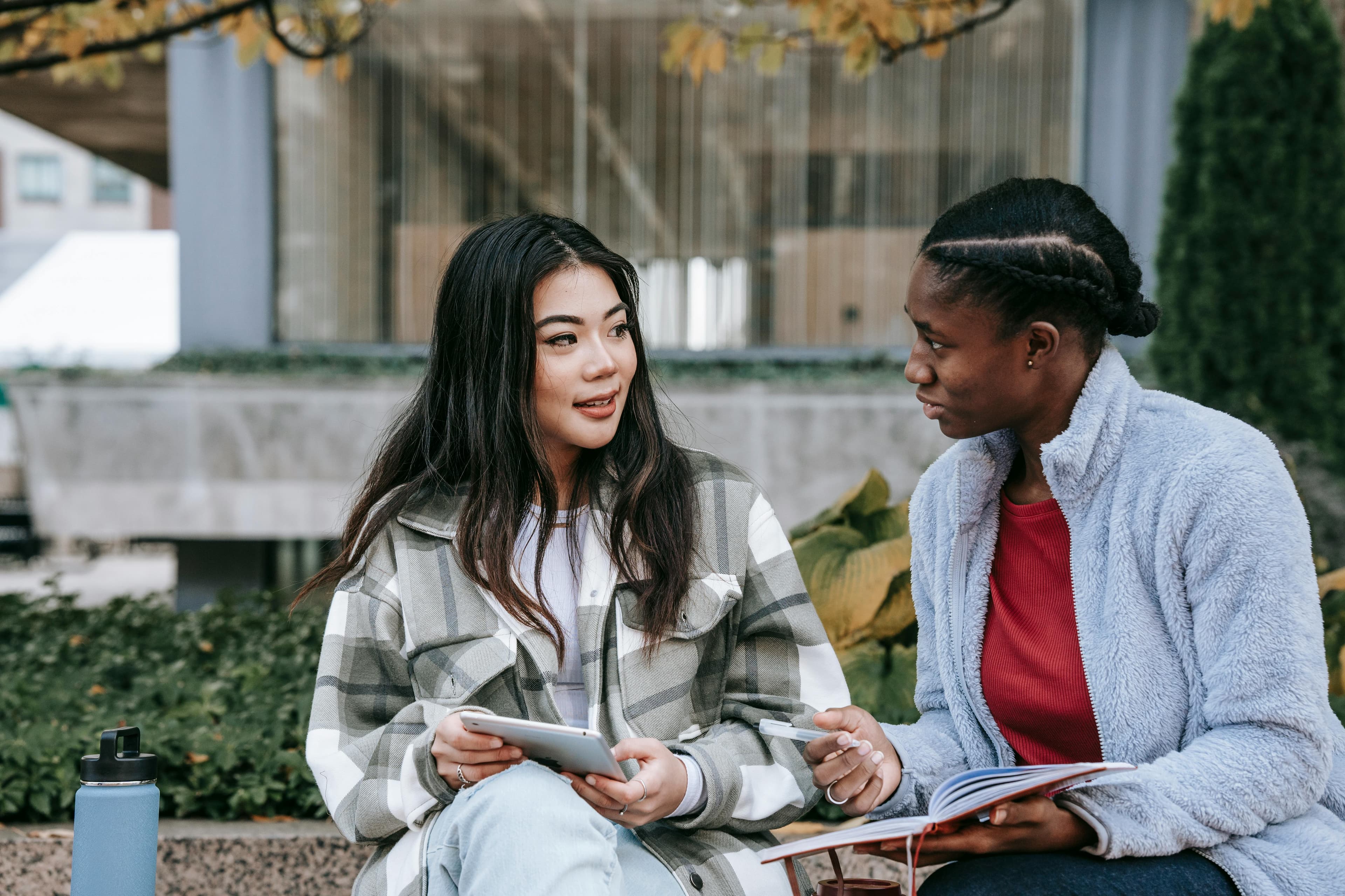 Two young women studying together outdoors
