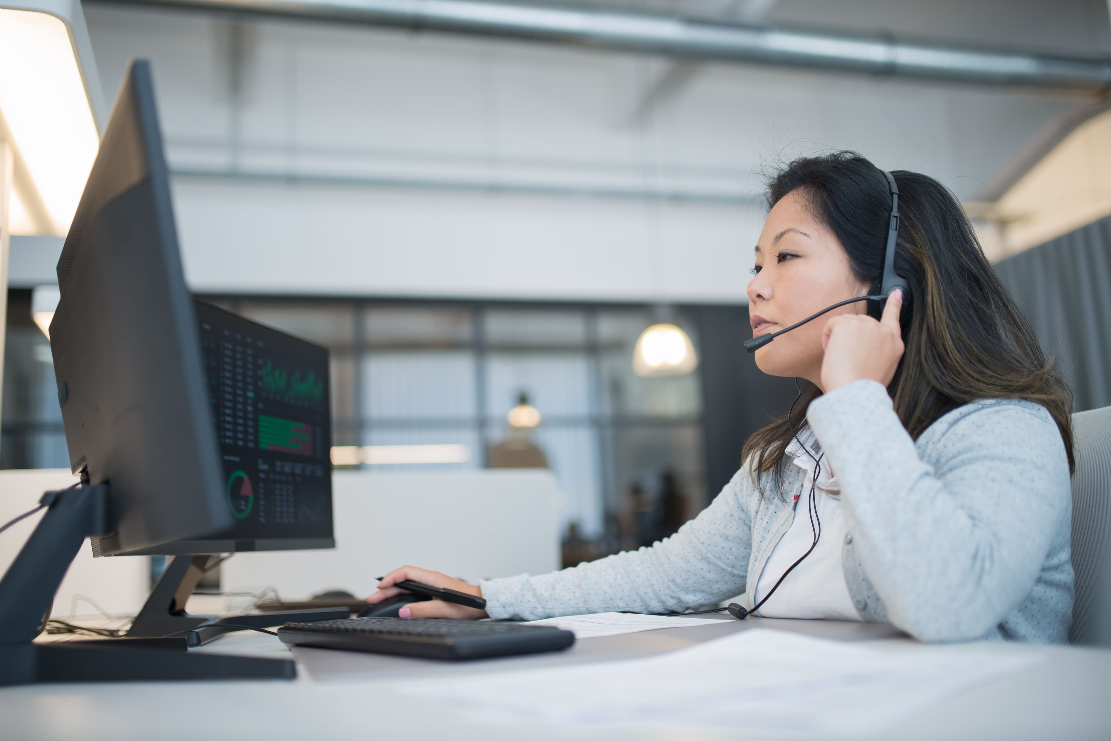 Woman wearing a headset working on customer support at a modern office desk