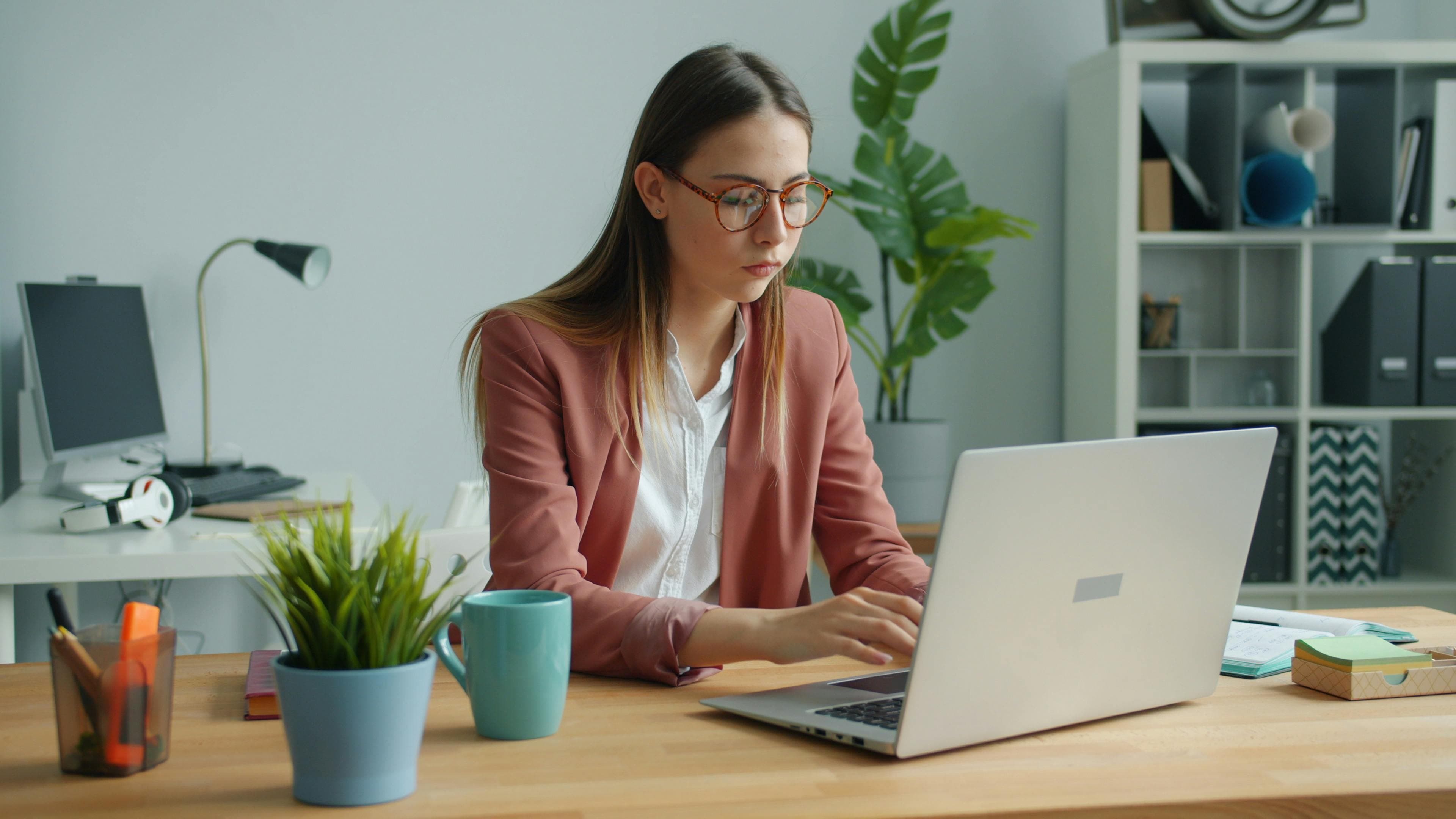 Focused professional woman using a laptop in a modern office setting