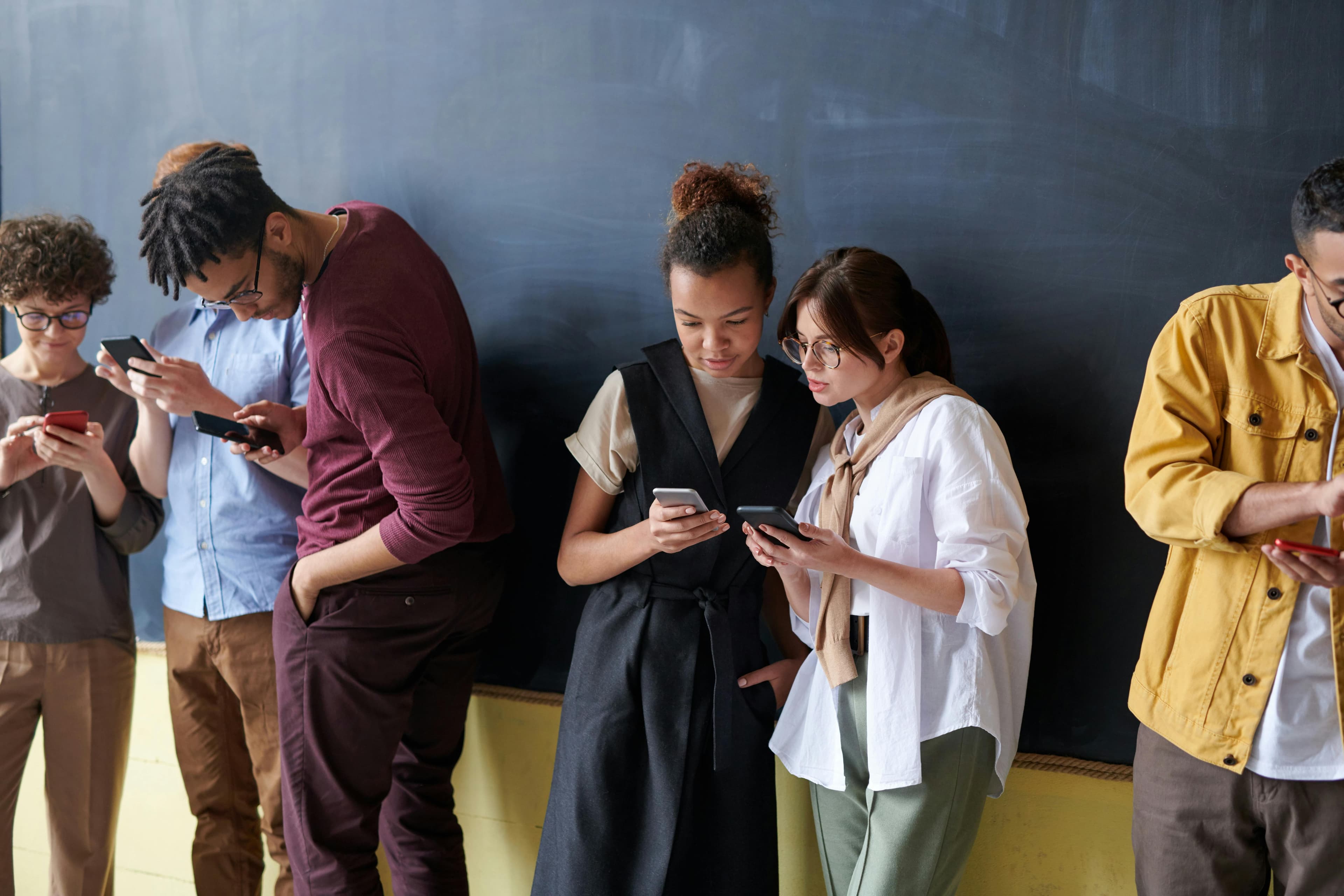 A diverse group of young adults using smartphones in a casual indoor setting