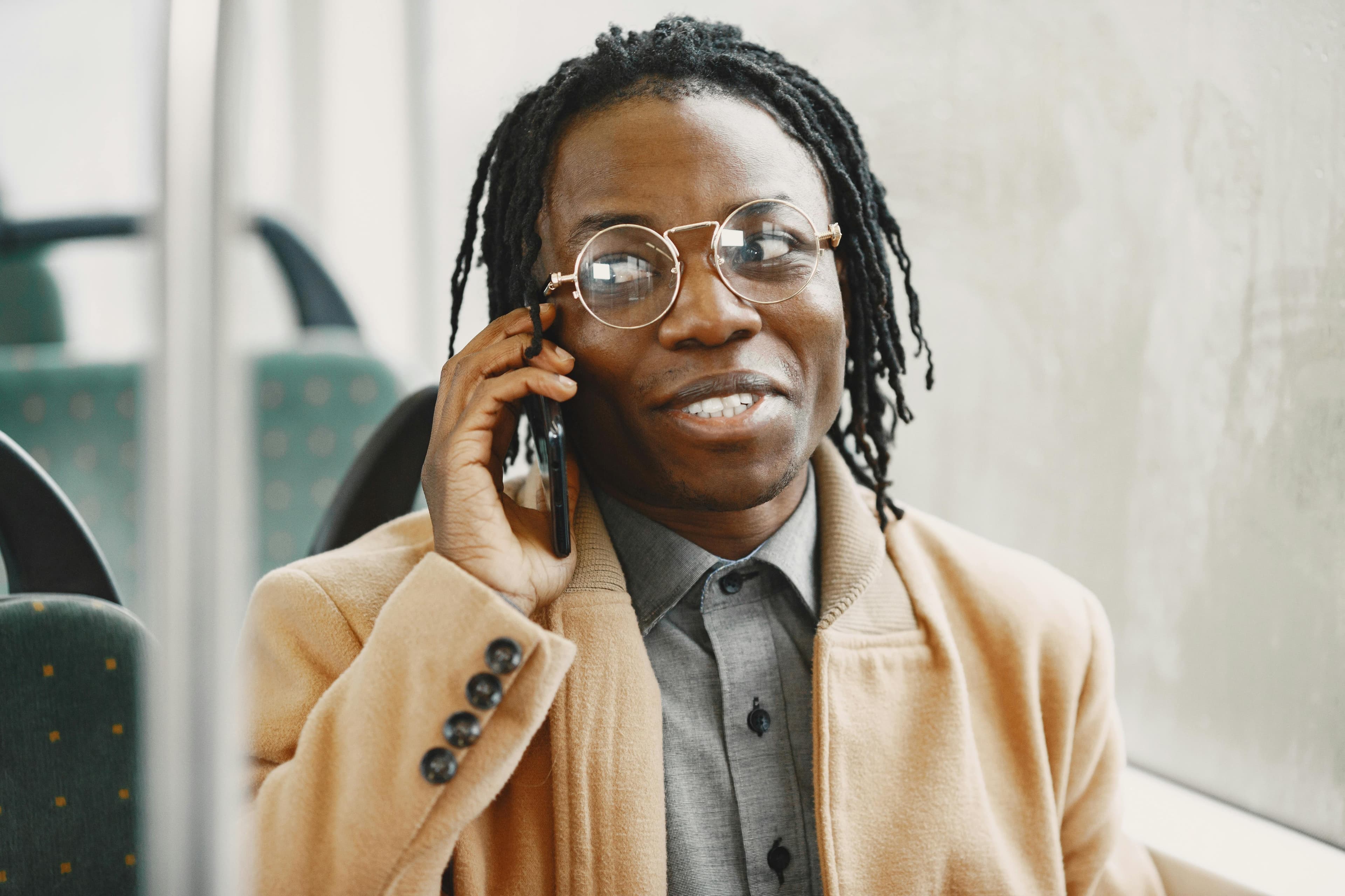 Man wearing glasses talking on a phone in public transport